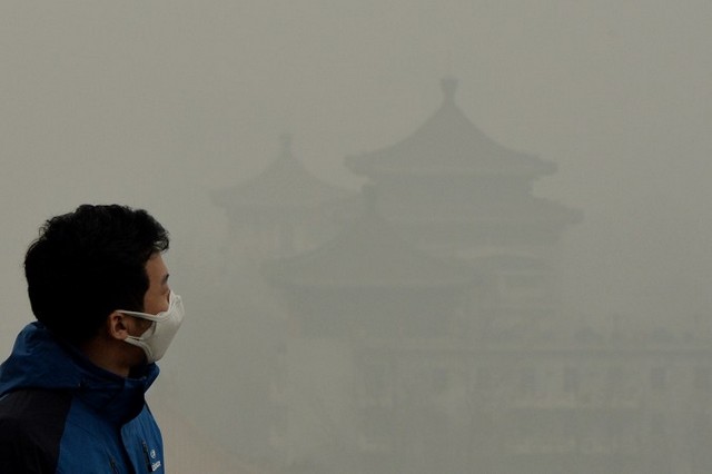 Турист у масці на пагорбі Цзіншань неподалік від Забороненого міста. Інтенсивне забруднення повітря і далі вкриває Пекін. 26 лютого 2014 року