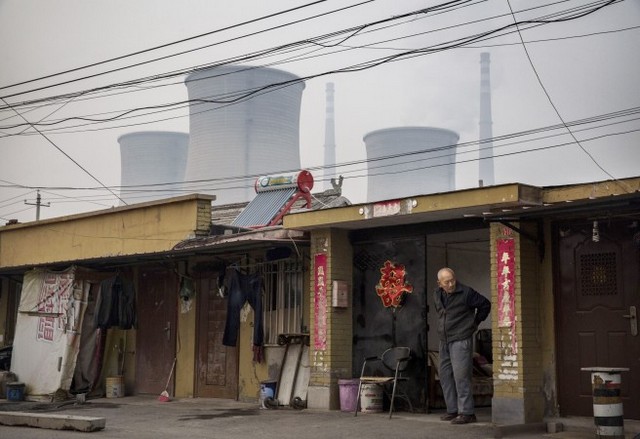 Китаец стоит перед своим домом на фоне угольной электростанции, Пекин, 19 ноября 2011 года