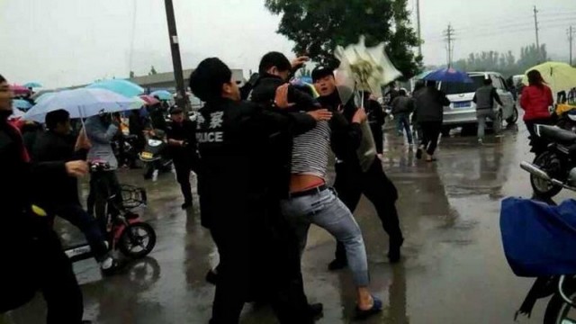 Полицейские атакуют протестующего, участвующего в демонстрации против загрязнения, вызванного химическим заводом в уезде Хоцзя города Синьсян провинции Хэнань, 15 сентября 2014 года. Протест длился семь дней. Скриншот: Weibo.com