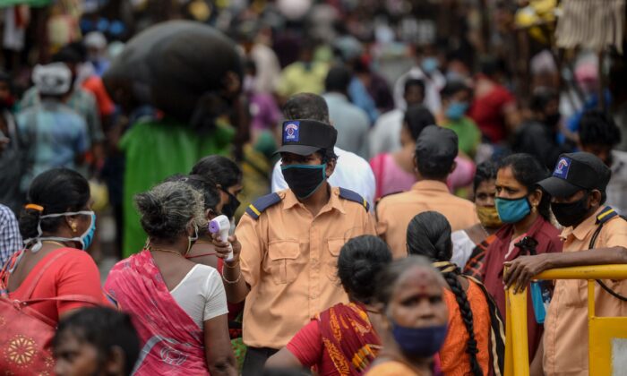 Співробітник служби безпеки перевіряє температуру жінки в Індії