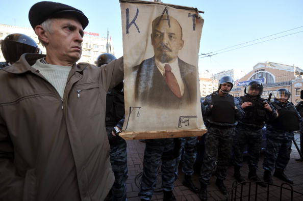 Мужчина держит плакат с надписью 'Ленин - палач' возле ОМОНа на акции украинских коммунистов во время открытия отреставрированного памятника Ленину. Киев, 27 ноября 2009 год. Фото: SERGEI SUPINSKY/AFP/Getty Images