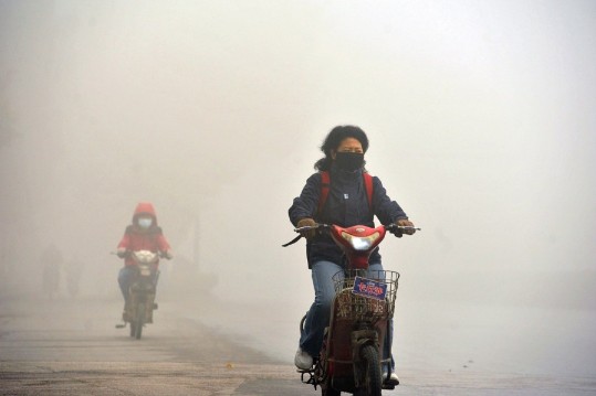 Местная жительница едет на мотоцикле с маской на лице в задымленный день. Южный Китай, Нанкин, 7 декабря. Скриншот: Netease/Велика Епоха